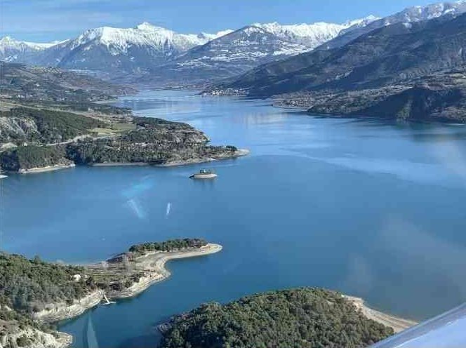 Grand lac entouré de montagnes enneigées vu depuis un avion léger.